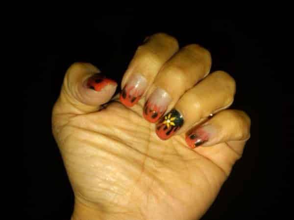 Ongles clairs avec flammes Harley Davidson et ongle noir unique avec fleur jaune