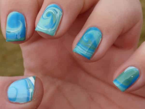 Ongles bleus avec des vagues blanches, bleues et vertes et des motifs en marbre