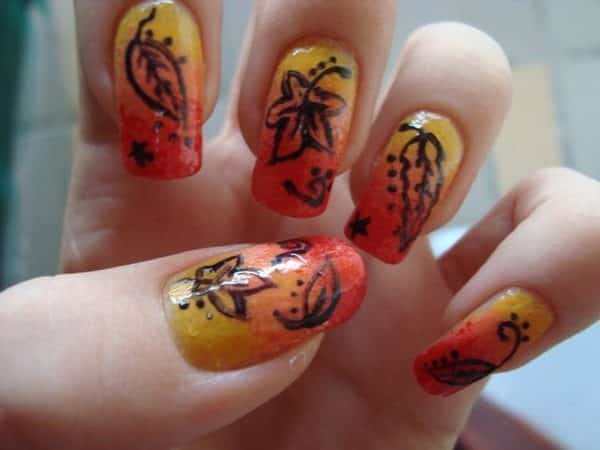 Ongles oranges, jaunes et rouges avec des feuilles brunes