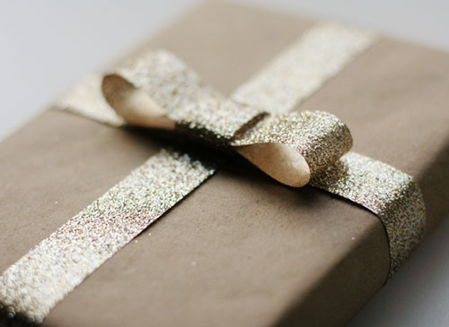 Emballage cadeau en papier kraft avec nœud à paillettes dorées