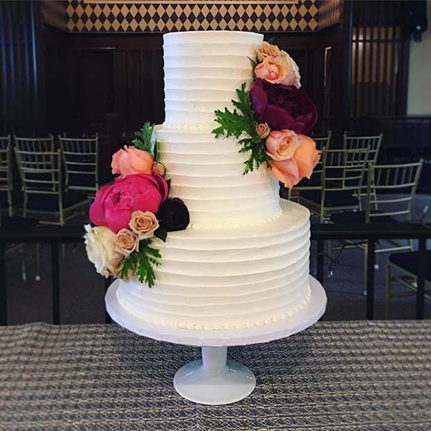 עוגת רב שכבתית לבנה קלאסית עם פרחים בהירים לעוגות חתונה בקיץ