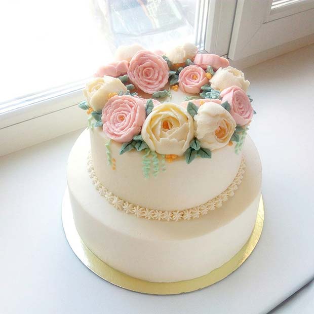 Κομψό κέικ δύο επιπέδων με απαλά λουλούδια για καλοκαιρινές γαμήλιες τούρτες