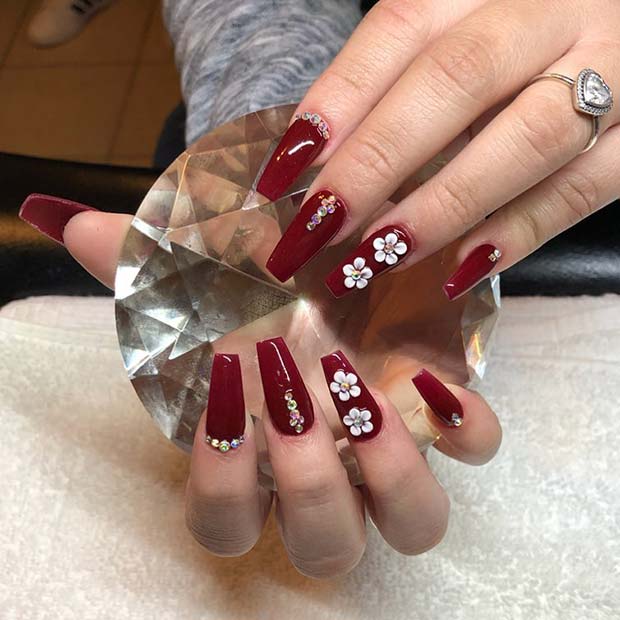 Ongles rouge foncé avec des fleurs et des strass