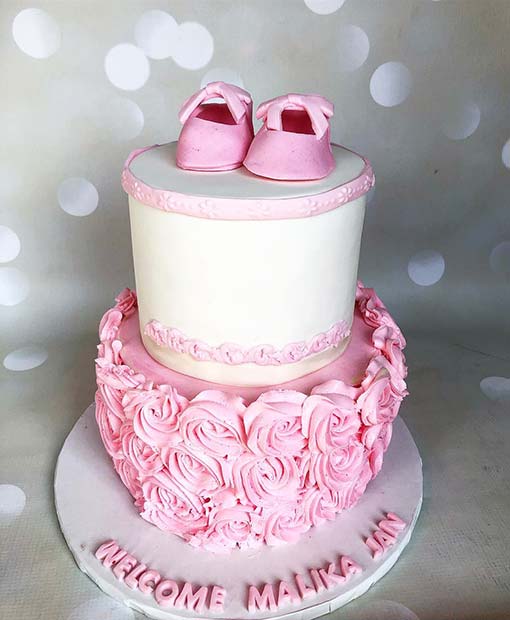 Gâteau rose et blanc avec d'adorables chaussures de bébé
