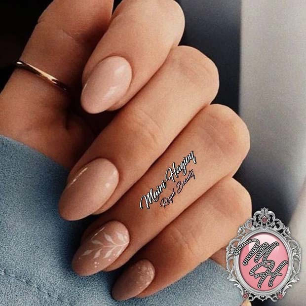 Ongles nude avec un nail art à feuilles blanches