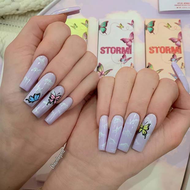 Ongles violets avec des nuages ​​et des papillons