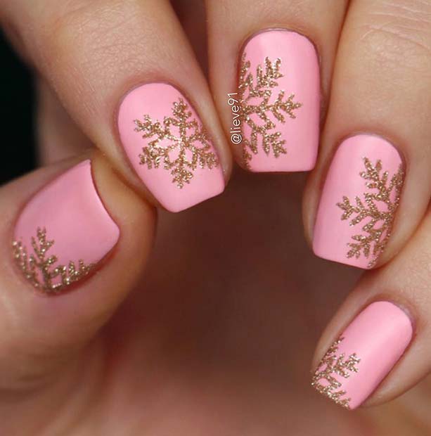 Ongles rose clair avec des flocons de neige dorés scintillants