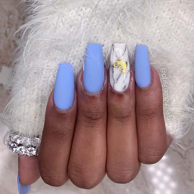 Ongles bleus avec art marbré et papillon doré