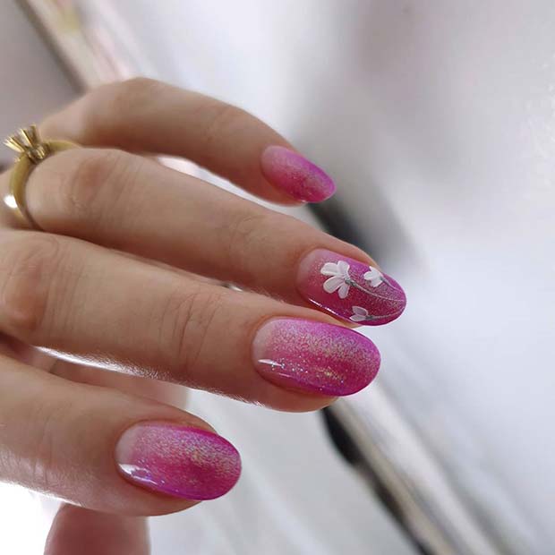 De jolis ongles pailletés roses avec une fleur blanche