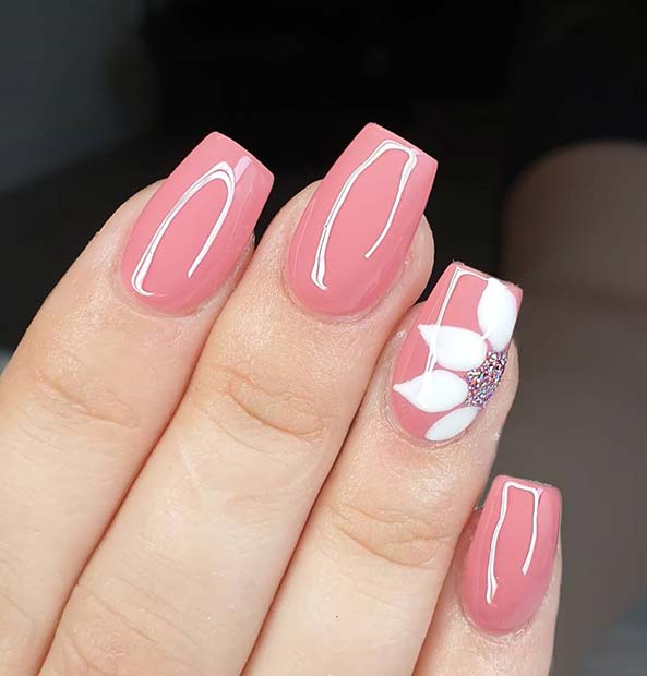 Ongles roses avec une fleur blanche