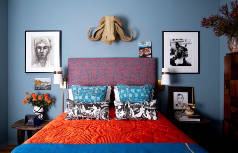 חדר שינה עם קירות כחולים ומצעים כתומים