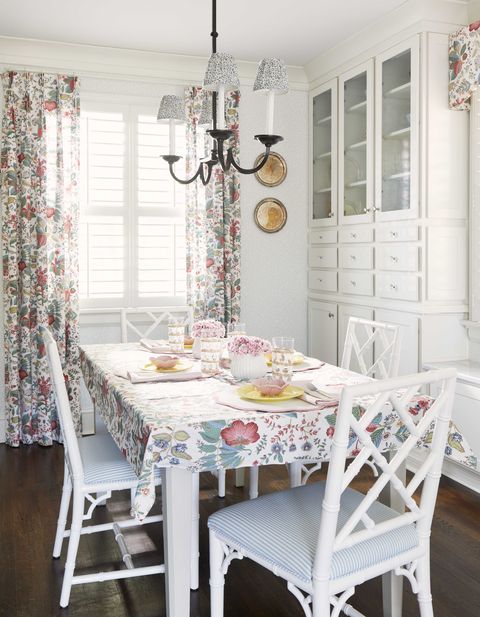 salle de petit-déjeuner, chaises de salle à manger blanches, coussins de chaise rayés blancs et bleus, rangements blancs, rideaux fleuris et dessus de table