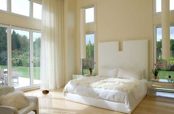 бяла спалня с големи стени и прозорци