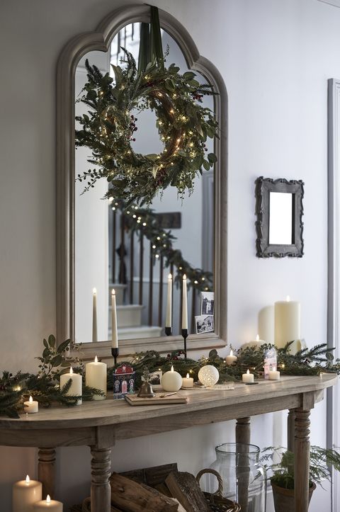עיטורי מסדר חג המולד עם זר מעל המראה ונרות על שולחן הקונסולה