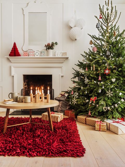 χριστουγεννιάτικο δέντρο στη γωνία ενός σαλονιού με ένα μεγάλο κόκκινο χαλί κάτω από ένα στρογγυλό ξύλινο τραπέζι και μια φλογερή φωτιά σε φόντο candi εκπληκτικό χαλί προσφέρει θαυμάσιο τρόπο για να φέρει ένα άλλο χρώμα στο δικό σας