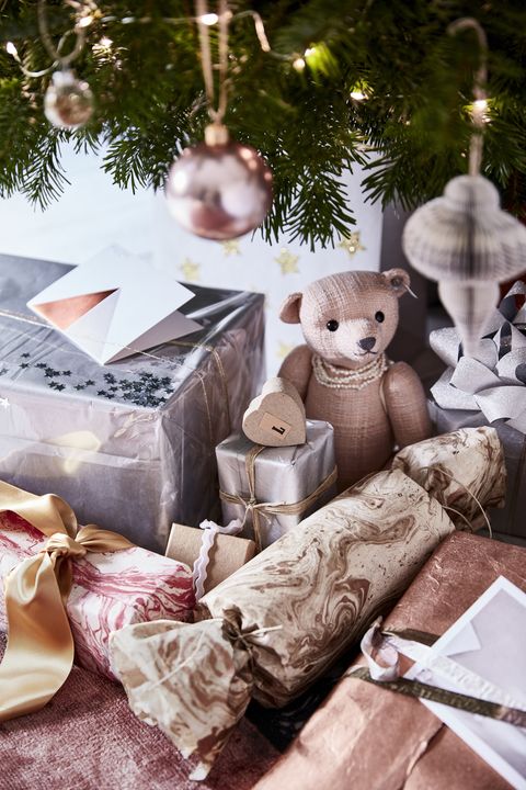 תקריב של מתנות מתחת לעץ חג המולד דובון קטן ומתנות עטופות בכסף וזהב מתנות יקרות מתנה מתנה עוטפת נגיעות זוהר על ידי שימוש בטפטים בגימור כסף, נחושת ומוצפים