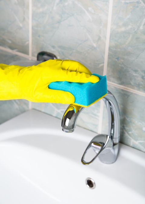 l'homme de désinfection pandémique dans des gants jaunes nettoie le robinet de la salle de bain et la femme de ménage du bain et de l'évier dans des gants de protection jaunes lavant le robinet de bain sale ou l'évier les mains de l'homme se lavent ou nettoient le bain en gros plan