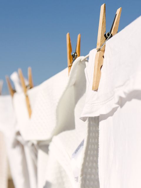 בגדים לבנים הסתובבו לייבוש על קו כביסה ברקע השמש החמה הבהירה הם שמיים כחולים בהירים