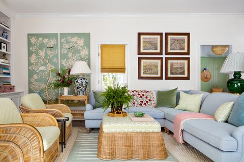 αγγλικό δωμάτιο, μπλε καναπές καναπέ, ψάθινο τραπεζάκι σαλονιού με πράσινο και λευκό μαξιλάρι καναπέ και πράσινα και άσπρα διακοσμητικά μαξιλάρια, ροζ χαλί, μεγάλη πράσινη λάμπα