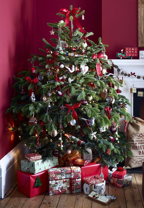 salon rouge vif avec corniche traditionnelle et cheminée, feu allumé, parquet, cadeaux emballés ci-dessous sapin de Noël décoré dans le coin de la pièce, décorations, guirlande, classique,