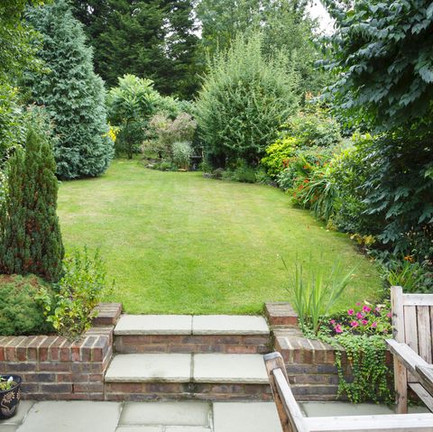 Jardin arrière en terrasses et paysager en Angleterre Royaume-Uni avec patio, herbe et marches en pierre