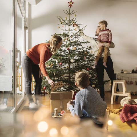 τετραμελής οικογένεια που διακοσμεί το χριστουγεννιάτικο δέντρο τους