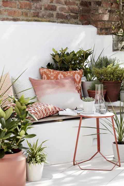 ιδέες κήπου, υπαίθριο καθιστικό γεμάτο με μαξιλάρια, φυτά και βοηθητικό τραπέζι