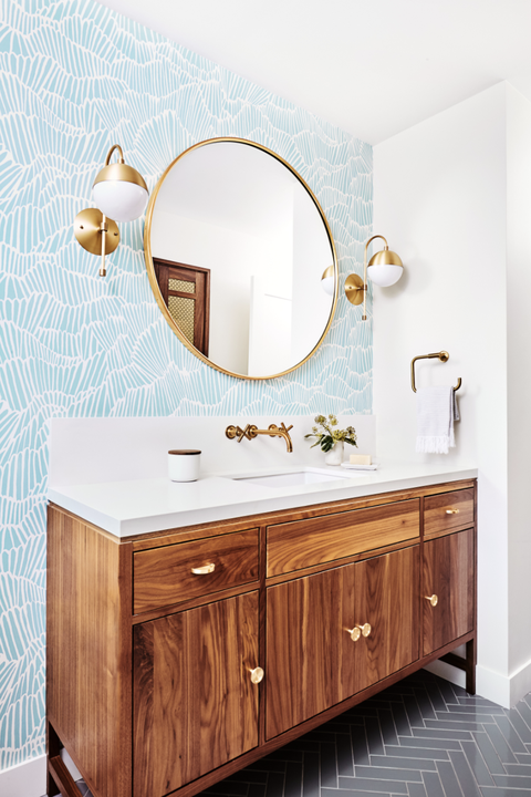salle de bain d'invités avec papier peint coquillage bleu clair et blanc, armoires marron, miroir doré