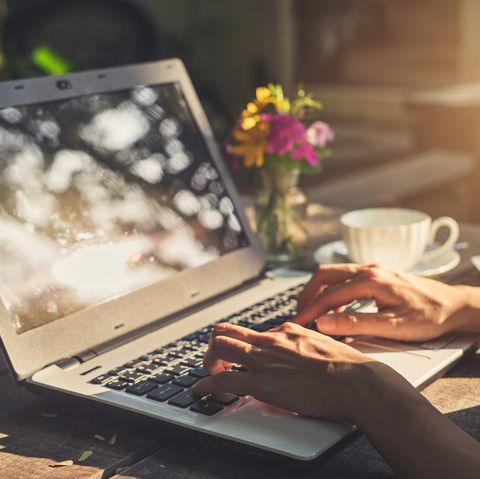 Taper à la main sur un ordinateur portable à clavier avec une tasse de café sur une table en bois