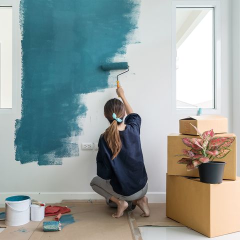 γυναίκα που ζωγραφίζει έναν τοίχο μπλε