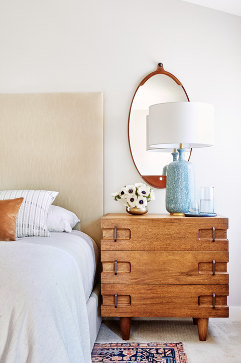 un côté de la chambre avec une table de chevet en bois, une lampe et un miroir