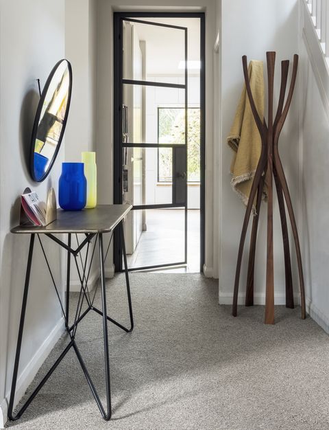 un couloir avec un tapis gris, un porte-manteau en bois, une petite table d'appoint, un miroir rond et un tapis de brume naturelle avec porte en verre à rayures crème, 3699 £ m², console fabio de moquette, 245 £, miroir petite friture vert graham, 400 £ , vases slivera bandaska, 195 £ chacun, jet de lin vice versa, 275 £ tout le support à lettres en laiton de la boutique conran, 72 £, porte-manteau amara flamingo par porado, 1 542 £, heal's