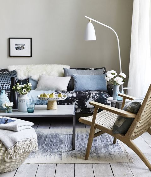 סלון עם כריות על הספה המעוצבת בכחול, מנורת רצפה לבנה כפופה מעל טיפות הקפה, דפוסי כתמים ופלטות למראה אימפרסיוניסטי עכשווי ומנוח