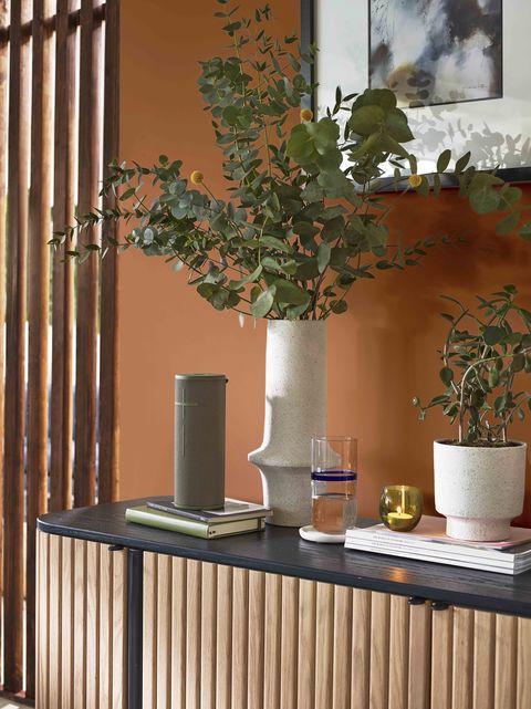 mur orange avec accessoires naturels et table d'appoint en bois