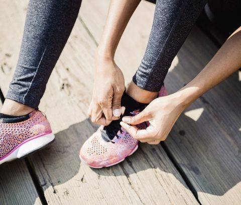 Athlète féminine assise sur le sol attachant ses coureurs