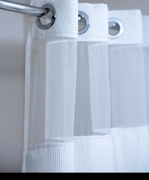 λευκή κουρτίνα ντους που κρέμεται από μια χρωμιωμένη κουρτίνα ντους