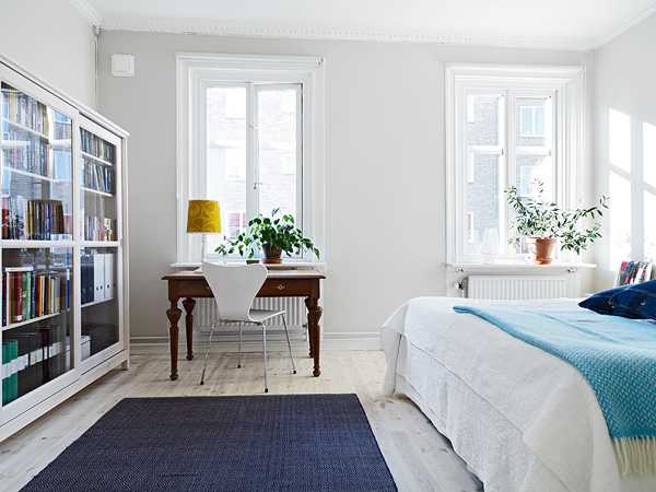 غرفة نوم بيضاء مع طاولة وخزانة ذات أدراج