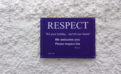 Plaque de rue dans les rues de Santorin demandant aux touristes de se comporter avec respect