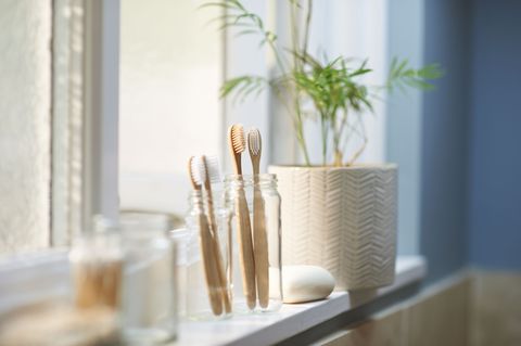 πλαστικές δωρεάν ξύλινες οικογενειακές οδοντόβουρτσες σε γυάλινο βάζο κατά μήκος άλλων μηδενικών απορριμμάτων στο περβάζι του μπάνιου