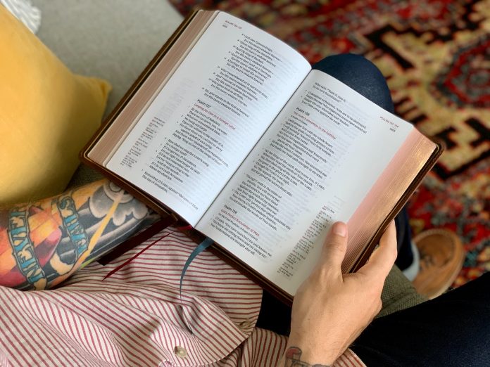 Ένας άντρας με τατουάζ διαβάζει μια Βίβλο.