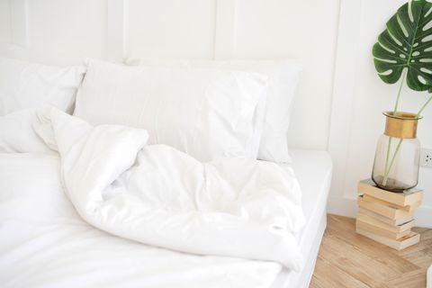 עוזרת מיטה עם כריות לבנות נקיות וסדינים בחדר שינה יופי מקרוב פנים