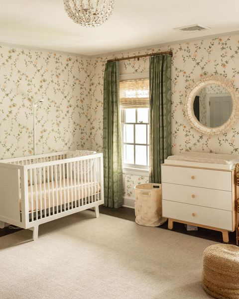 חדר ילדים, טפטים פרחוניים, וילונות ירוקים, עריסה לבנה, שידה לבנה ועץ, שטיח באזור עירום